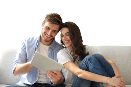 Young couple watching media content online in a tablet sitting on a sofa on a transparent background
