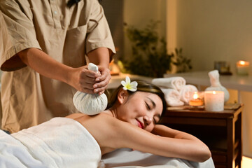 Spa body massage treatment with hot herbal ball for deep relaxation. Woman having massage in the spa salon