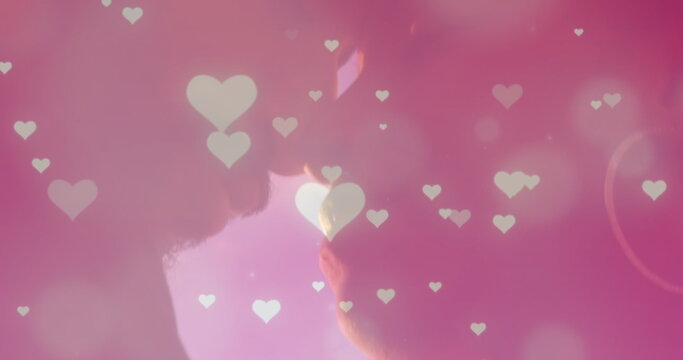 Image of glowing spots and hearts over diverse couple embracing