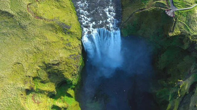 Skogafoss waterfall in the springtime. Vibrant green grass. Slow motion aerial view