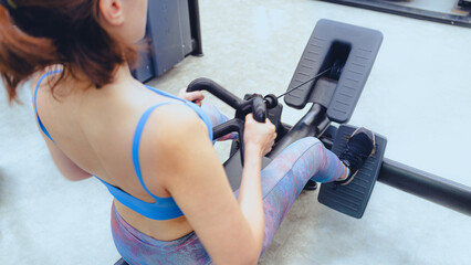 Movement in motion: A fit and focused young woman in sportswear is actively working out on a rowing machine