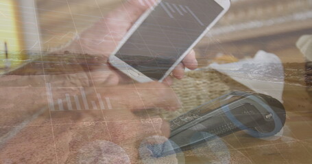 Image of financial data and graphs over hands of caucasian man using payment terminal