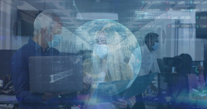 Image of globe and data over diverse coworkers in face masks in office