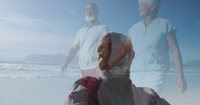 Image of african american senior man over african american senior couple walking on beach - Powered by Adobe