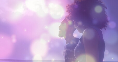 Image of light spots over couple at beach