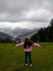 Naklejka premium A woman standing on top of a lush green hillside with her arms outstretched