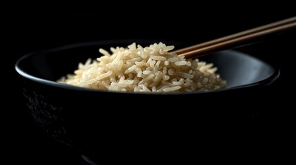 Close-up of a bowl of rice with chopsticks on a dark background. Perfect image to show healthy eating or Asian cuisine.