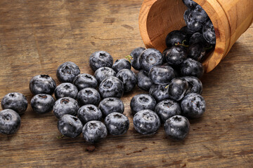 Fresh ripe whole blueberries on rustic wood background mini wooden bucket blue berry
