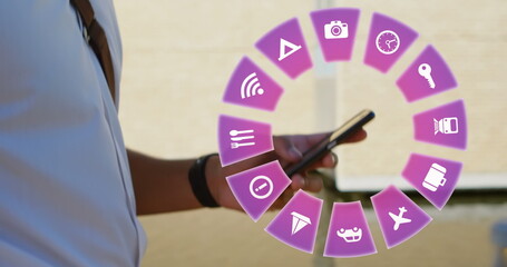 Image of travel icons and caucasian man using smartphone in background