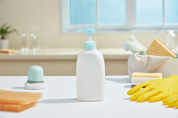 Natural daylight illuminates a kitchen counter filled with soft-colored cleaning supplies, portraying cleanliness with warmth and modern simplicity. White pump bottle unlabeled, mockup for design