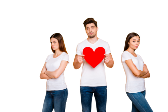 Portrait of one nice attractive doubtful guy holding in hands heart deciding between two offended girlfriends dilemma isolated over bright vivid shine yellow background