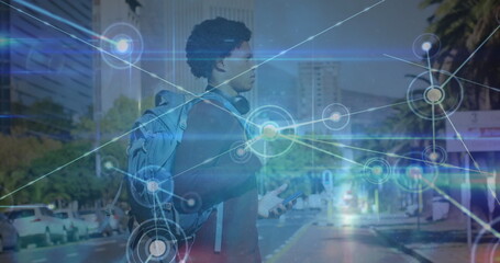 Fototapeta premium Image of network of connections over african american man with smartphone crossing the street