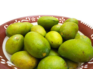 Fresh green mango fruit in a basket isolated on white background, closeup, tropical fruit, unripe mangoes for pickle