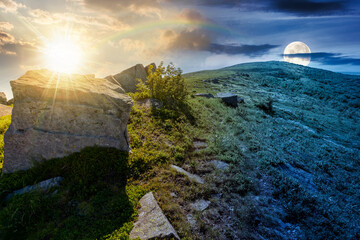 boulder on a hill under blue sky with clouds in summer. day and night time change concept. huge sandstone among the grass. path to the mountain top with sun and moon at twilight