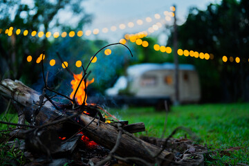 Cozy Night Campfire by Vintage Trailer with String Lights in Garden