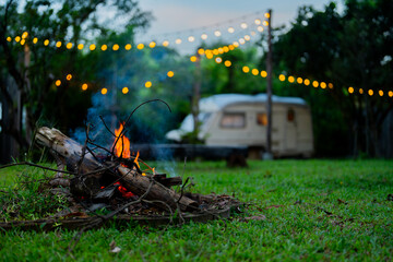 Cozy Night Campfire by Vintage Trailer with String Lights in Garden
