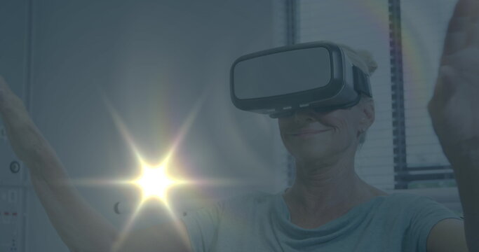 Image of light spots over caucasian businesswoman using vr headset in office