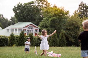 A family with three children. A mother with many children and toddlers in a summer park. Children are walking and flying a kite. Large families, family values, and leisure time with children.