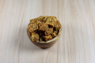 Fried tempeh in small cubes in a round teak bowl.