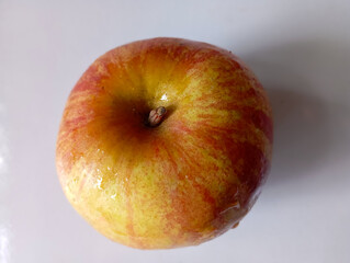 Jonagold apples in a wooden bowl, captured from a bird's eye view. Their skin displays a beautiful mix of yellow and red stripes, with visible speckles.