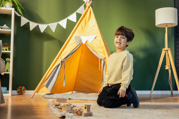 Happy child playing with wooden toys in his room with teepee tent © MexChriss