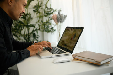 Close-up side view of a mature businessman working on a laptop with charts on screen, Financial...