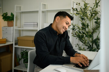 Fototapeta premium A Mature Businessman Multitasking on Phone and Laptop, Modern Professional Communication
