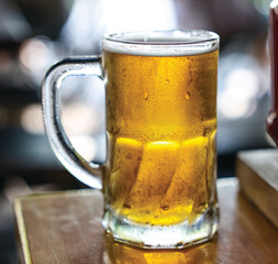 Image of a cold beer mug. The mug is of clear glass, highlighting the golden and bright color of the beer.