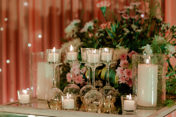 Elegant candle display on mirrored surface, with floral arrangement in soft lighting creating a warm, celebratory atmosphere.