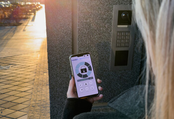 A Person's Hand Holding Smartphone For Disarming Security System Of Door