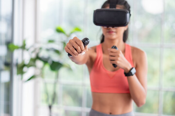 Asian woman wear virtual reality glasses and train boxing with joystick control at home
