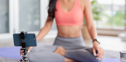 asian trainer woman live streaming online about wellness exercise at home.Influrencer marketing