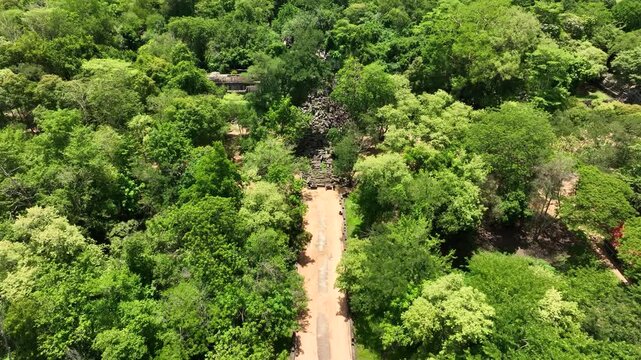 Aerial dolly view above forest trail to hidden ruins at Beng Mealea