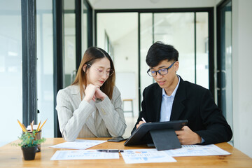 Two business people discuss financial strategy and collaborate with colleagues.