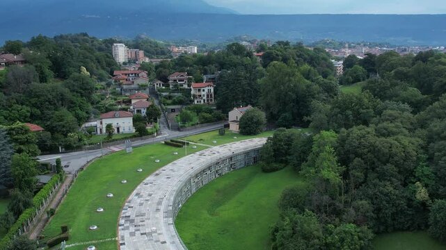 Talponia, the semi-subterranean residential unit in Ivrea, Piedmont, designed by Gabetti Isola in 1968, set in a curved green park at the city forest edge, drone pull away shot slow motion, Italy