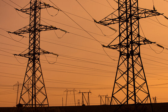 High-voltage power line in the field. Electricity pylons in the evening. Electric tower. Power transmission lines. energy security and clean energy.  