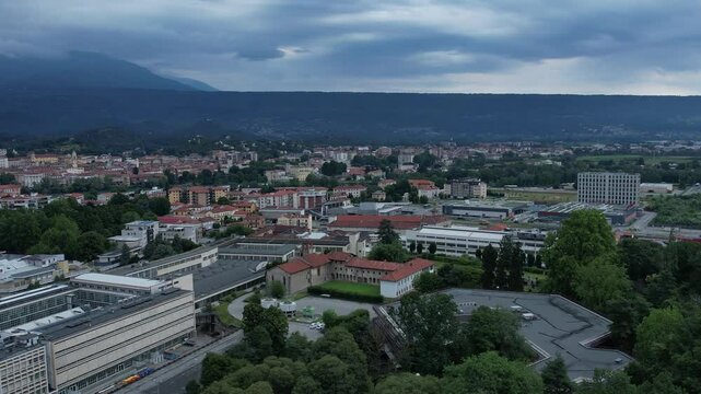 Group of buildings in Ivrea's Unesco-listed Olivetti district, framed by the Alps and Mount Mombarone in the background, drone shot, slow motion, sunny and cloudy sky, Piedmont, Italy
