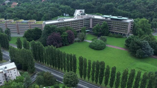 Drone view of the Nuovo Palazzo Uffici Olivetti by architect Gino Valle in Ivrea, Italy, hallmark of modernist corporate architecture now used by TIM, framed by green lawns, drone, slow motion.