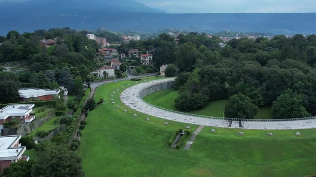 Talponia, the semi-subterranean residential unit in Ivrea, Piedmont, designed by Gabetti Isola in 1968, set in a curved green park at the city forest edge, pull out drone shot slow motion