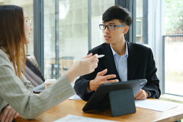 Two business people discuss financial strategy and collaborate with colleagues.
