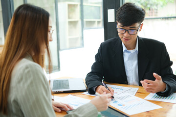 Two business people discuss financial strategy and collaborate with colleagues.