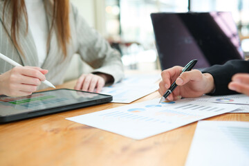 Two business people discuss financial strategy and collaborate with colleagues.