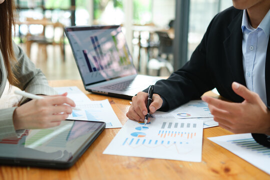 Two business people discuss financial strategy and collaborate with colleagues.