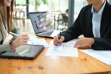 Two business people discuss financial strategy and collaborate with colleagues.