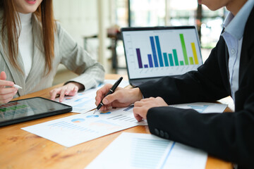 Two business people discuss financial strategy and collaborate with colleagues.