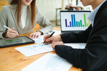 Two business people discuss financial strategy and collaborate with colleagues.