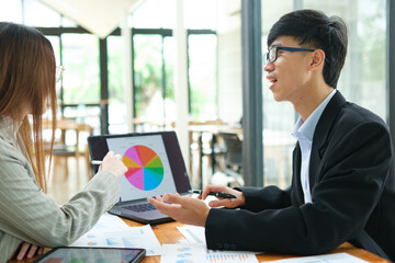 Two business people discuss financial strategy and collaborate with colleagues.