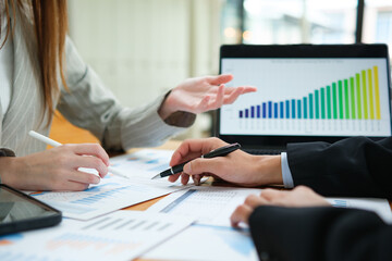 Two business people discuss financial strategy and collaborate with colleagues.