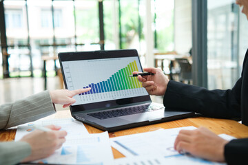 Two business people discuss financial strategy and collaborate with colleagues.