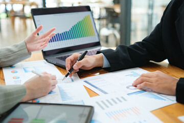Two business people discuss financial strategy and collaborate with colleagues.